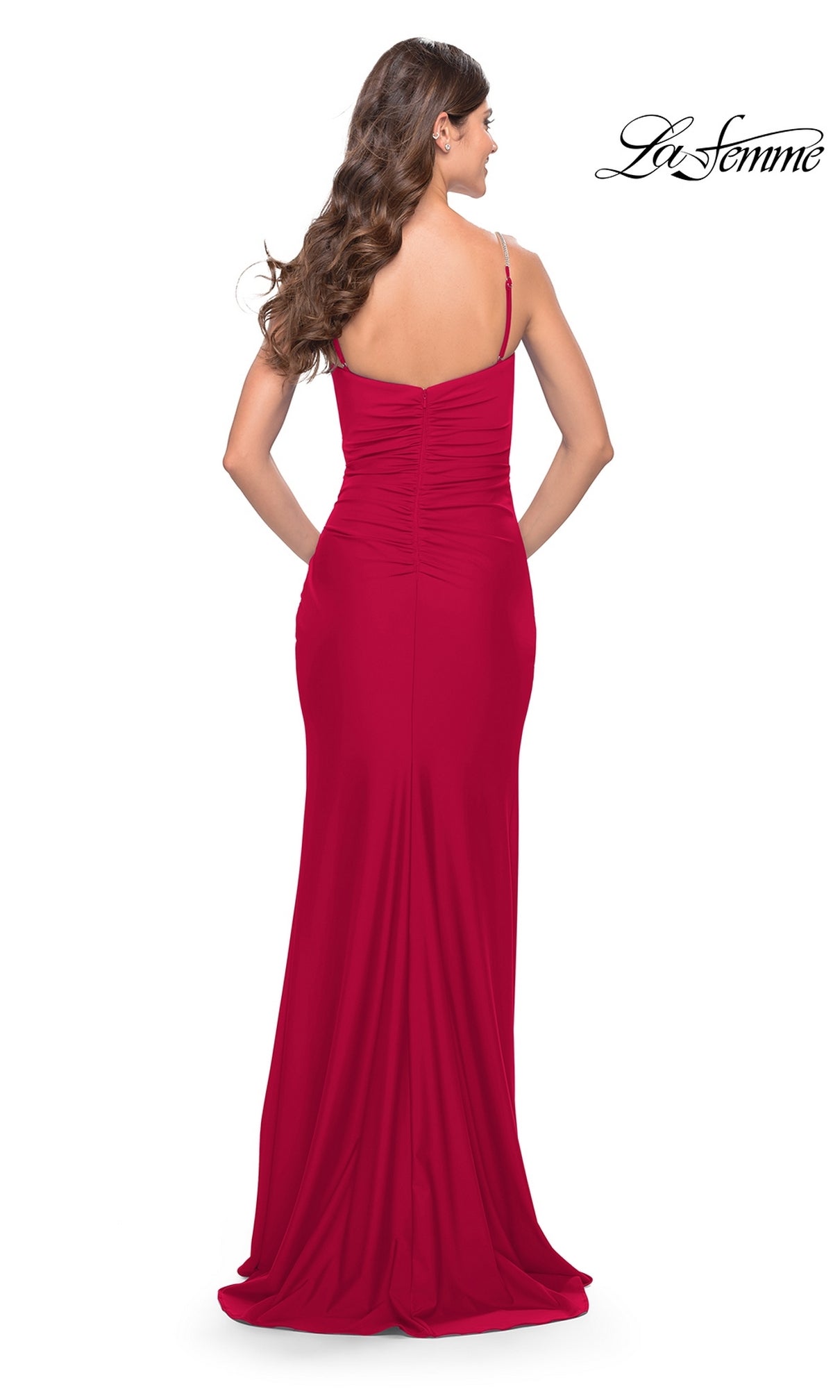 A woman models the La Femme Wrap-Style Long Prom Dress 31107—a floor-length, sleeveless red gown with ruched back detail—standing against a white background with the